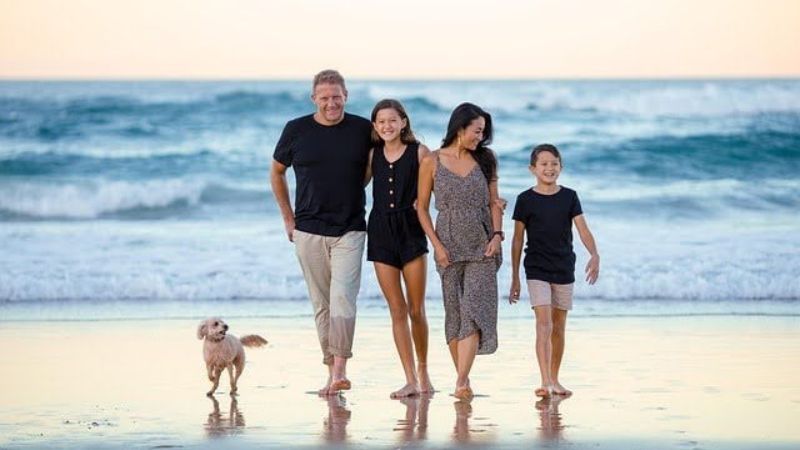 Family with two kids and a small dog walking on the beach.