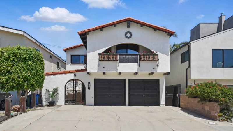 Two-story white house with black garage doors and red tile roof.