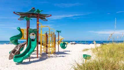 Colorful playground set on a sandy beach.
